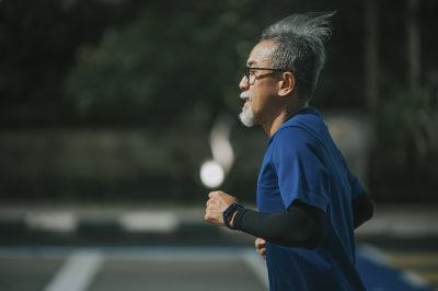 Senior man running on city street.