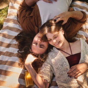 The picture shows two people lying on a blanket outdoors on the grass.