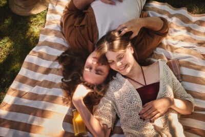 The picture shows two people lying on a blanket outdoors on the grass.