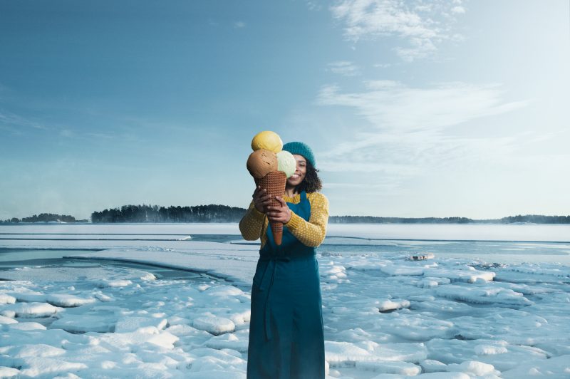Henkilö seisoo jäätyneen meren edustalla ja pitää käsissään isoa jäätelötötteröä