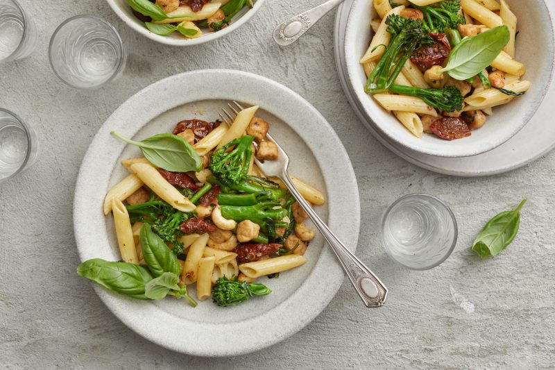 Vegepastaa kolmella lautasella. Vegepastassa on pennepastaa, broccolini, aurinkokuivattua tomaattia ja basilikaa sekä kasvisproteiinia.