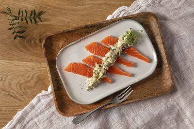 Jouluinen lohiannos lautasella puisen tarjoiluvadin päällä