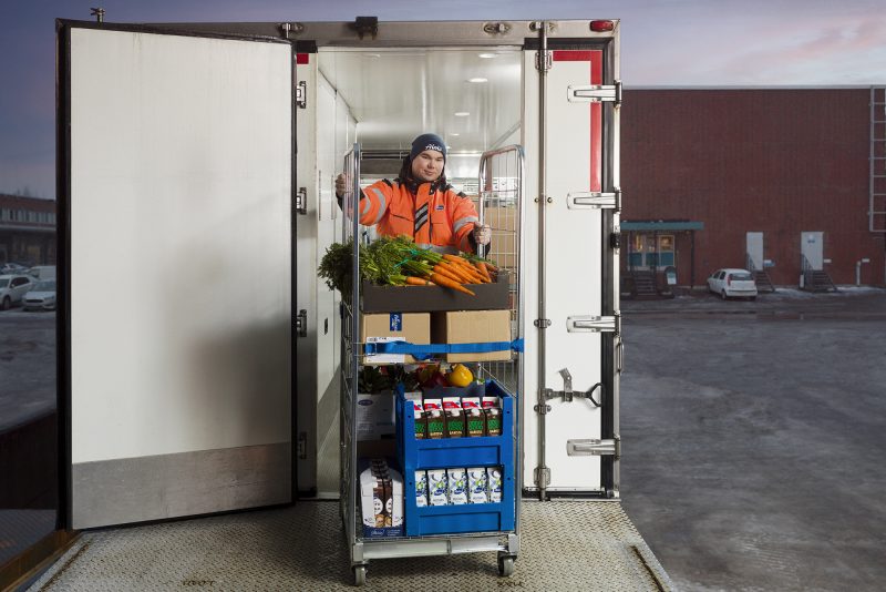 Kuljettaja lastaa kuorma-autoon ravintolaan toimitettavaa rullakkoa täynnä raaka-aineita