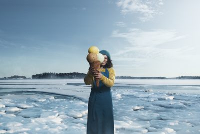 Henkilö seisoo jäätyneen meren edustalla ja pitää käsissään isoa jäätelötötteröä