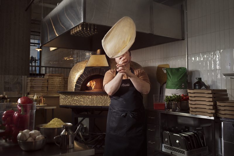 Kokki heittää pizzataikinaa ilmaan ammattikeittiössä