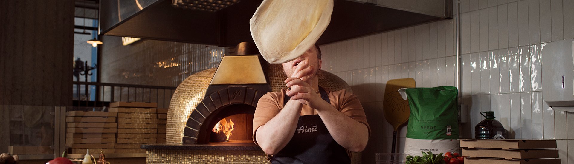 Kokki heittää pizzataikinaa ilmaan ammattikeittiössä