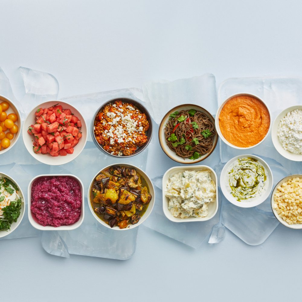 Ylhäältä alaspäin kuvattu salaattibuffetin järjestys, vasemmalla vihreää salaattia, keskellä tahnoja ja täytteitä ja oikeassa reunassa itse proteiinit.