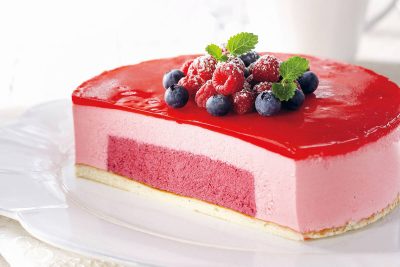 Värikäs punainen kakku, joka sivusta leikattu auki, jotta kakun rakenne näkyy.