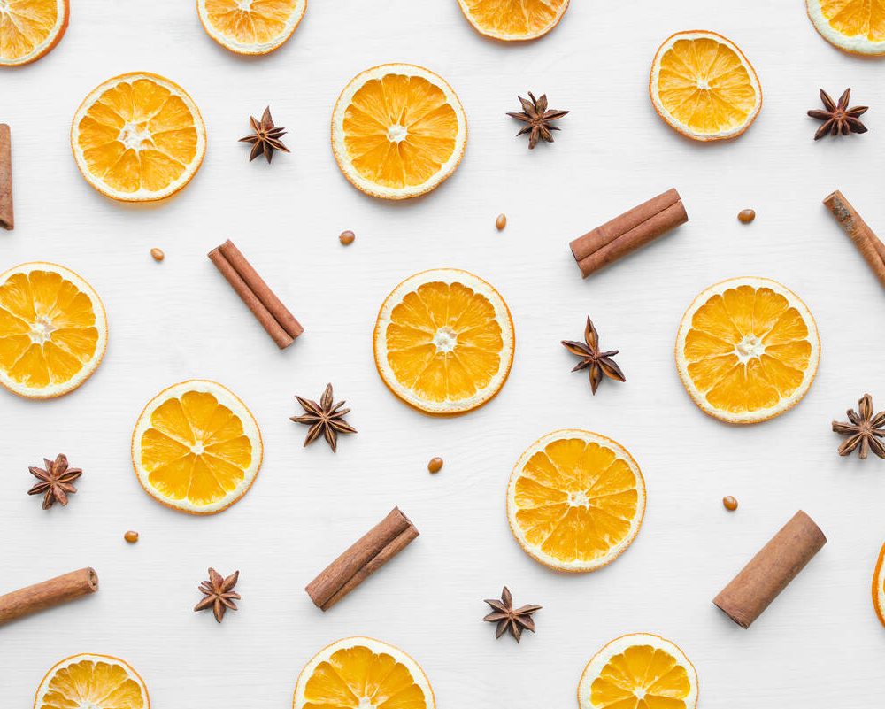 Christmas frame composition with dry oranges, cinnamon sticks and anise stars over white wooden background. Flat lay, top view, happy holiday concept